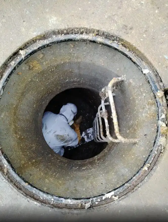 Técnico de Destapes Bravo trabajando dentro de una cámara de alcantarillado abierta