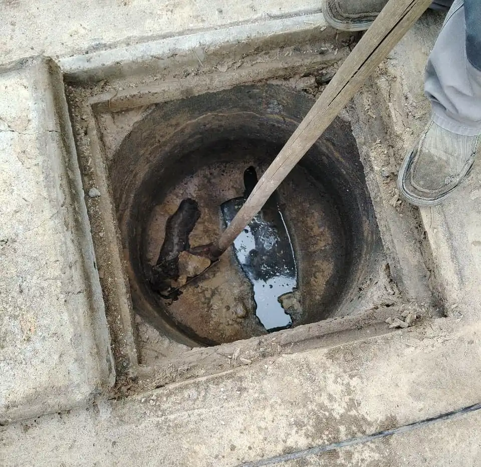Cámara de alcantarillado abierta con la varilla trabajando la obstrucción