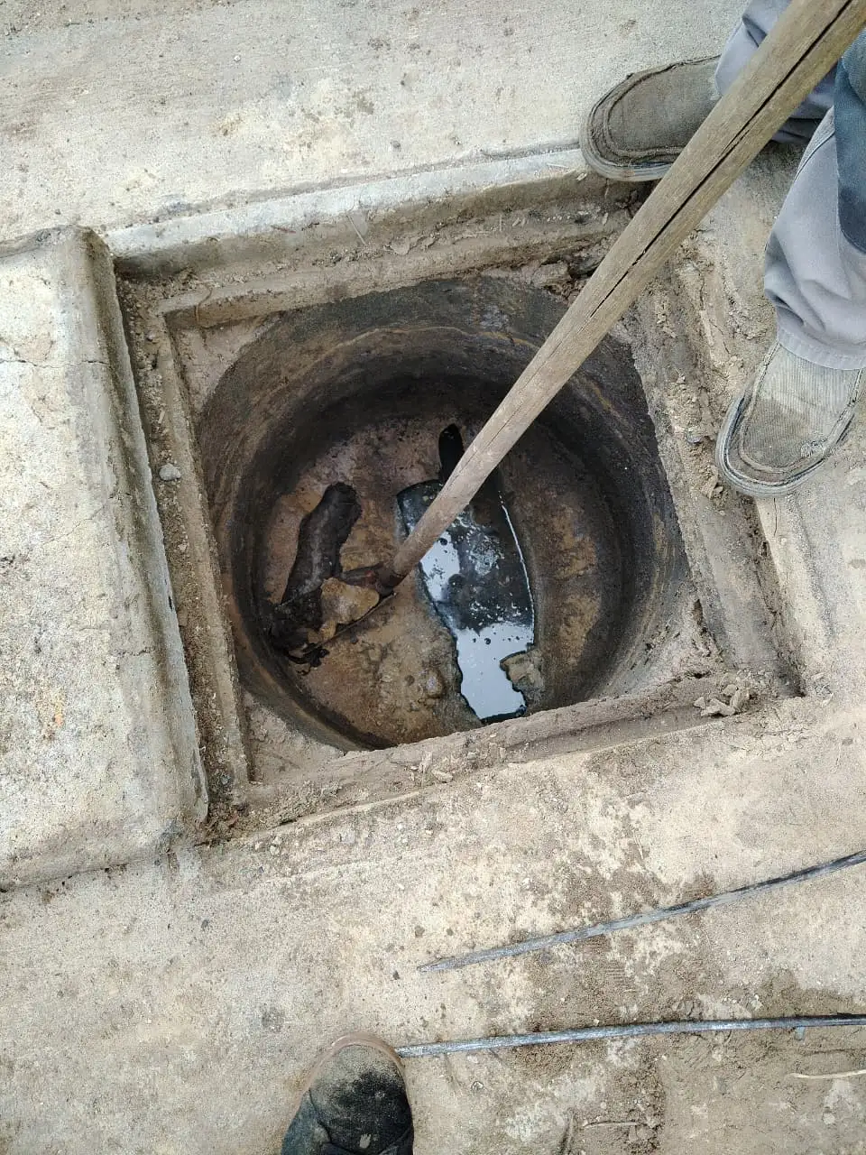 Cámara de alcantarillado abierta con la varilla trabajando la obstrucción